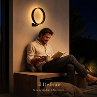 Hombre leyendo con taza de té en banca de porche bajo ANELLO I encendido de noche