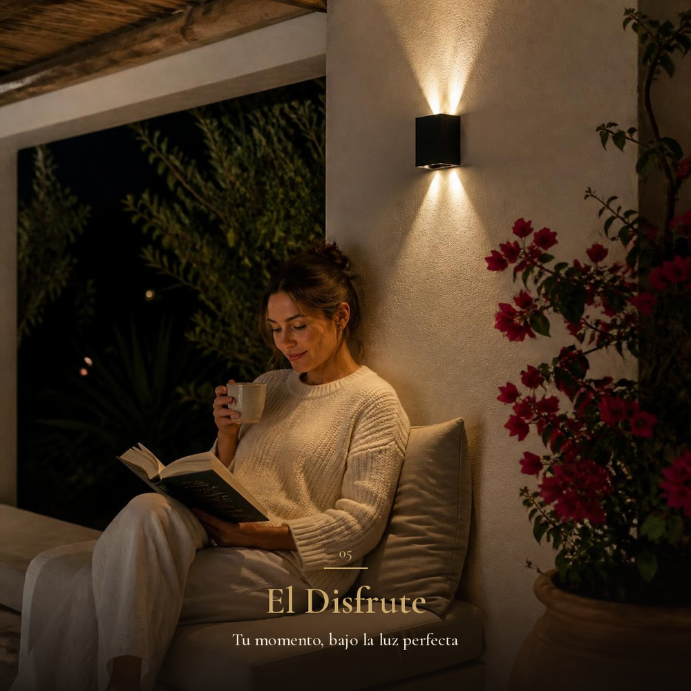 Mujer leyendo con té en porche de noche bajo la luz cálida de BANNOR