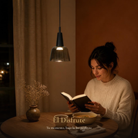 Mujer leyendo y cenando sopa en mesa redonda de roble bajo la luz cálida de BUBUP en la noche