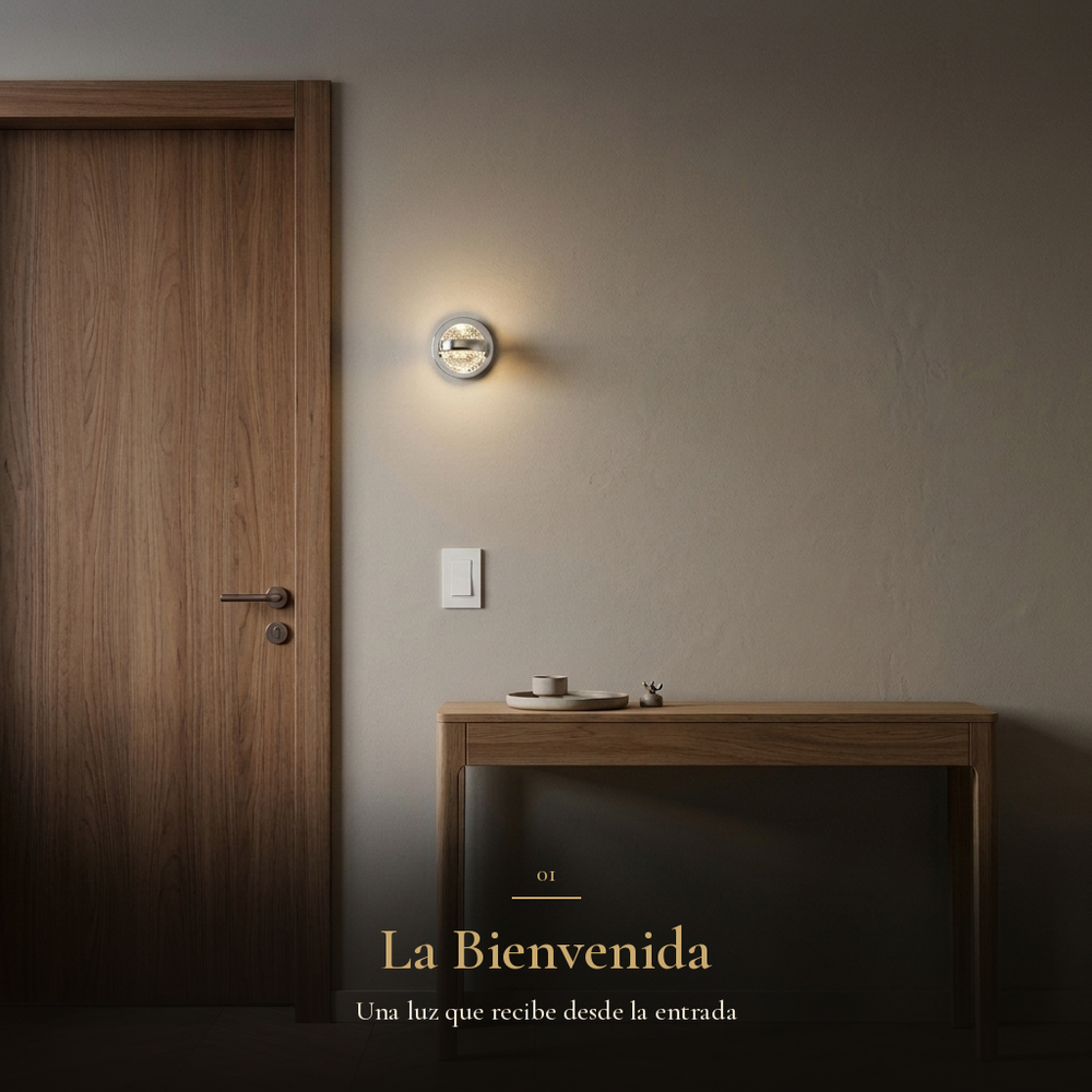 La Bienvenida: arbotante BURBIA WALL encendido en el recibidor junto a la puerta de nogal y la consola