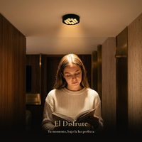 El Disfrute: mujer leyendo un libro bajo la luz cálida del plafón HIVE PTL II en un pasillo de noche