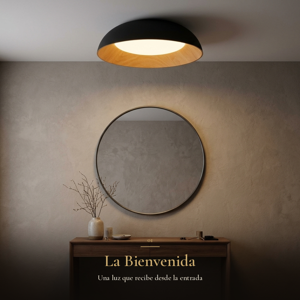 La Bienvenida: plafón LEGNO encendido sobre consola de nogal y espejo redondo en el recibidor