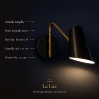 Acercamiento de NARELLA encendido en muro azul marino: pantalla dirigible, brazo latonado curvo, base E27 hasta 60 W, pantalla 12.8 × 20 cm, proyección 42.5 cm