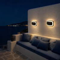 Dos PARUMELO en muro de terraza con sala exterior frente al mar de noche
