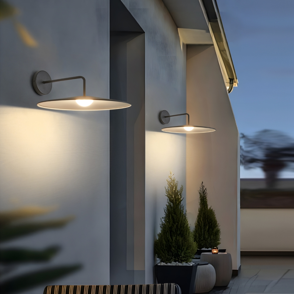 Dos TITA I encendidos en fachada blanca de terraza con plantas