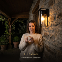 El Disfrute: mujer con taza bajo la luz cálida del farol VEGA II en porche de piedra de noche